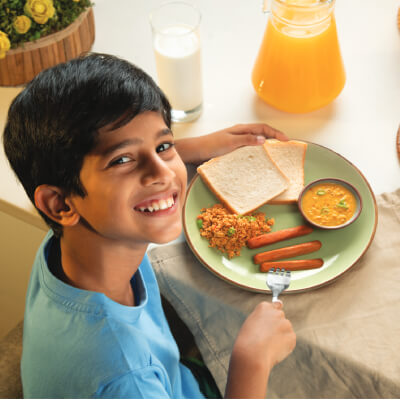 A kid enjoying a breakfast with Keels sausages