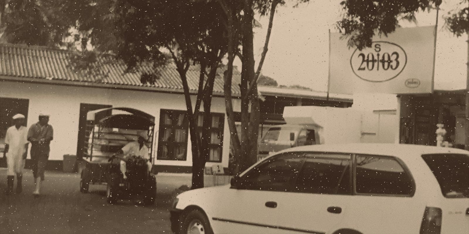 Black and White image of group of people with a car and a tractor